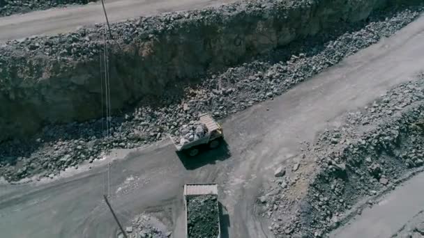 Camiones volquete mineros en gran mina de granito a cielo abierto. Cargado camiones paseos en carretera cantera repisa drone persecución vista superior — Vídeo de stock