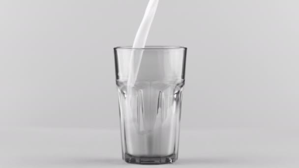 Lait versé dans un verre facetté fermé isolé sur fond gris clair — Video