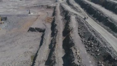Büyük granit açık maden ocağında maden kamyonları. Boş kamyonlar taş ocağının kenarına gidiyor İHA takip üst görünümü