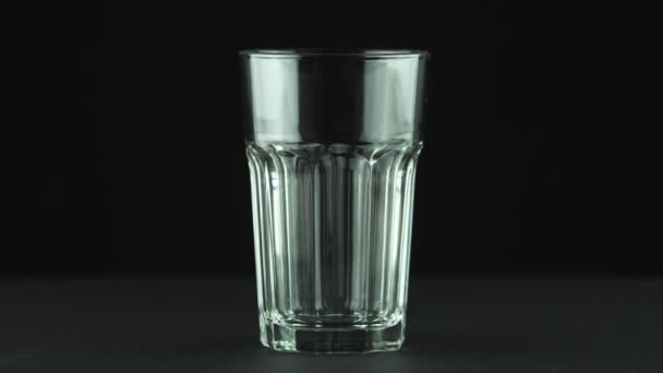 Milk pouring into faceted glass close up isolated on black background — Stock Video