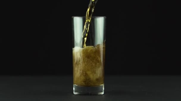 Cola est versé dans du verre plein de bulles et de mousse isolée sur fond noir — Video