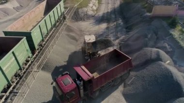 Öndeki yükleyici inşaat lojistik merkezindeki çöp kamyonuna çakıl yüklüyor.