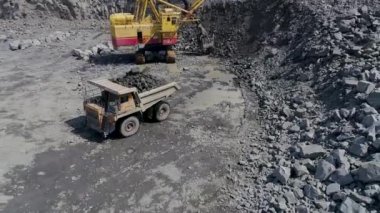 Mikashevichi, Belarus, 14.04.2020 - Büyük kazıcı graniti ağır çöp kamyonuna yüklüyor