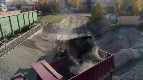 Cargador frontal carga grava en el cuerpo del camión de volteo en el centro logístico de la construcción — Vídeo de stock