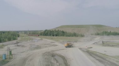 Mikashevichi, Belarus, 14.04.2020 - Ağır kamyonet Belaz yeşil kaya damlalarının arka planında ağır çekimde gidiyor