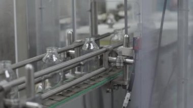 Tıbbi çözüm taşıyıcı hattındaki cam şişeler kapalı.