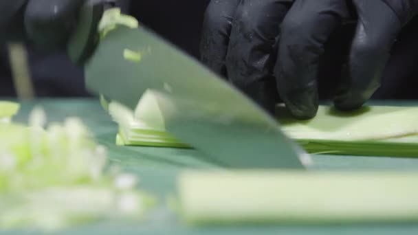 Cooks händer i svarta handskar skivning purjolök närbild — Stockvideo