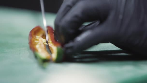 Cooks hands in black gloves chopping chili peppers close up selective focus — Stock Video