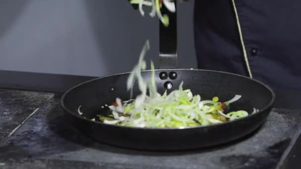Шеф-повар наливает овощи в кастрюлю на плиту — стоковое видео