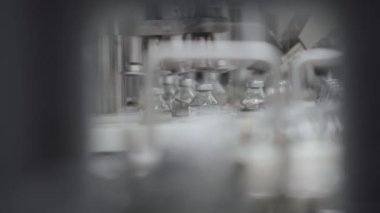 Plastik ve alüminyum kaplamalarla doldurulmuş cam şişeler tıbbi çözüm taşıyıcı hattı seçici odak noktasını kapatın