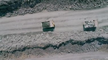 Büyük granit açık maden ocağında maden kamyonları. Yüklü kamyonlar taş ocağı drone takip üst görünümü üzerinde geziniyor