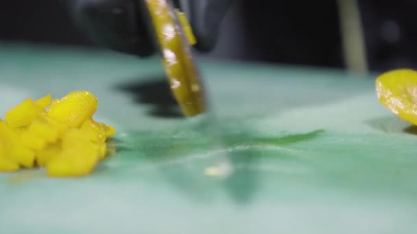 Кухарі рук в чорних рукавицях рубають жовтий перець крупним планом — стокове відео