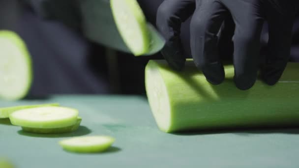 Kookt handen in zwarte handschoenen snijden courgette close-up selectieve focus — Stockvideo