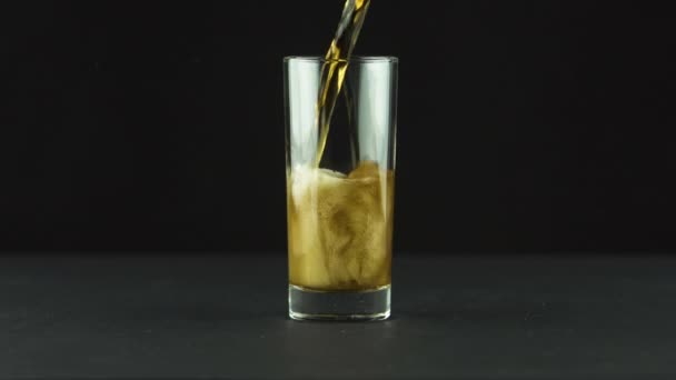 Cola is poured into glass full of bubbles and foam isolated on black background — Stock Video