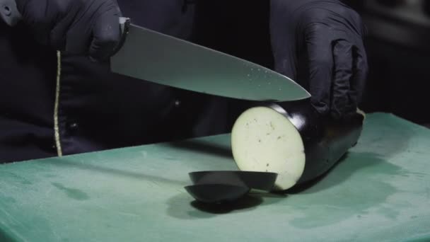 Cooks hands in black gloves chopping eggplants close up — Stock Video