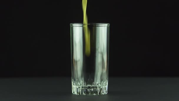 Juice pouring into glass isolated on black background — Stock Video