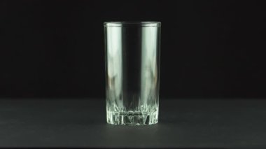 Siyah arka planda izole edilmiş köpük ve kabarcıklarla dolu bardağa kola dökülür.