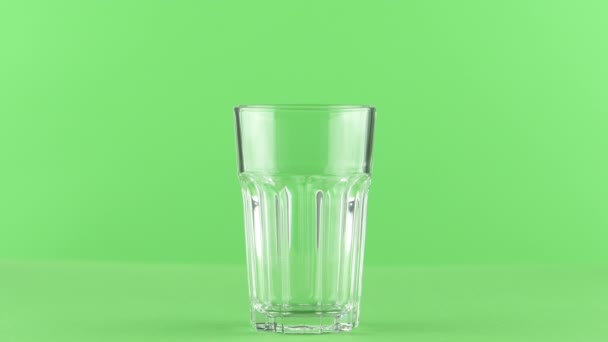 Milk pouring into faceted glass close up isolated on light green background — Stock Video