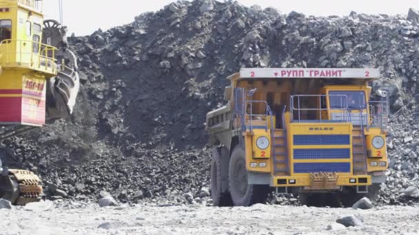 Mikashevichi, Belarus, 14.04.2020 - Big excavator loading granite into heavy dump truck Belaz — Stock Video