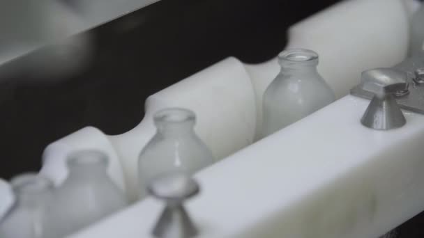Glazen flessen op transportband medische oplossing close-up selectieve focus — Stockvideo