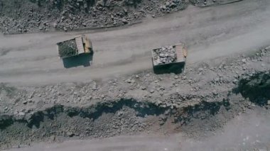 Büyük granit açık maden ocağında maden kamyonları. Taş ocağında yüklü kamyon gezintileri İHA kovalamacası ağır çekim