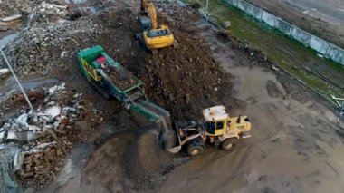 Minsk, Belarus 13.04.2020 - Beton ağır inşaat ekipmanlarının endüstriyel geri dönüşümü: ön yükleyici, kazıcı, inşaat atığı hava görünümünün geri dönüşümü üzerinde çalışan beton ezme istasyonu