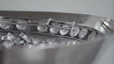 Tıbbi çözüm taşıyıcı hattında cam şişeler için alüminyum kapaklar seçici bir odak noktası