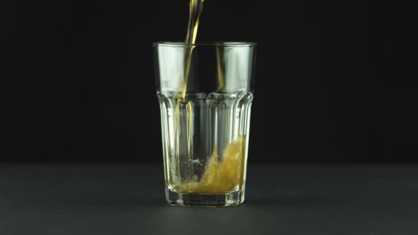 Cola hälls i facetterat glas fullt av bubblor och skum isolerad på svart bakgrund — Stockvideo