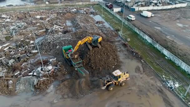 Minsk, Bielorrusia 13.04.2020 - Reciclaje industrial de equipos pesados de construcción de hormigón: cargadora frontal, excavadora, estación de trituración de concreto que trabaja en el reciclaje de residuos de construcción vista de drones — Vídeo de stock