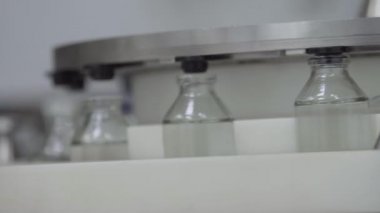 Tıbbi çözüm taşıma hattında plastik kapaklarla doldurulmuş ve mühürlenmiş cam şişeler.