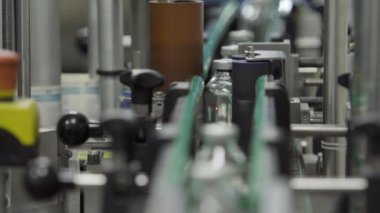 Plastik ve alüminyum kaplamalarla doldurulmuş cam şişeler tıbbi çözüm taşıyıcı hattı seçici odak noktasını kapatın