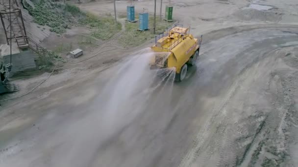 Mikashevichi, Belarus, 14.04.2020 - heavy-duty watering machine pours water onto ground to reduce dust generation in industrial production of granite crushed stone slow motion — 비디오