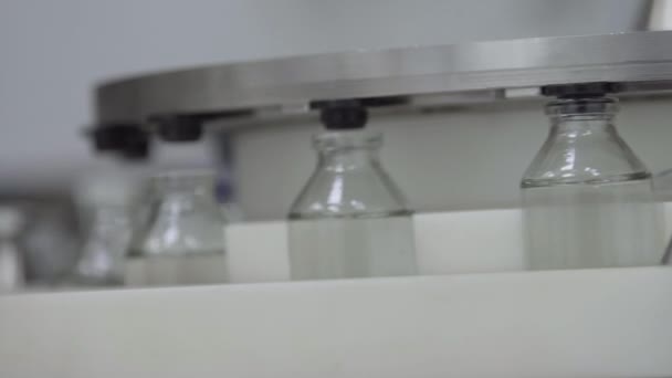 bouteilles en verre remplies et scellées avec des bouchons en caoutchouc sur une ligne de convoyeur de solution médicale fermer 