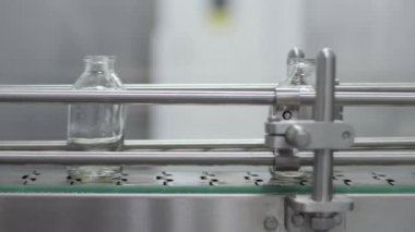Tıbbi çözüm taşıyıcı hattındaki cam şişeler kapalı.