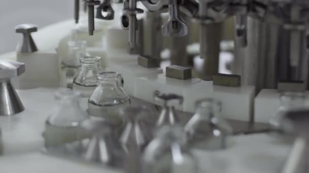 Bouteilles en verre sur un convoyeur de solution médicale à la station de remplissage close up focus sélectif — Video
