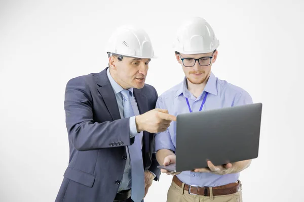 Twee ingenieurs in harde hoeden bespreken nieuw project tijdens het gebruik van laptop — Stockfoto