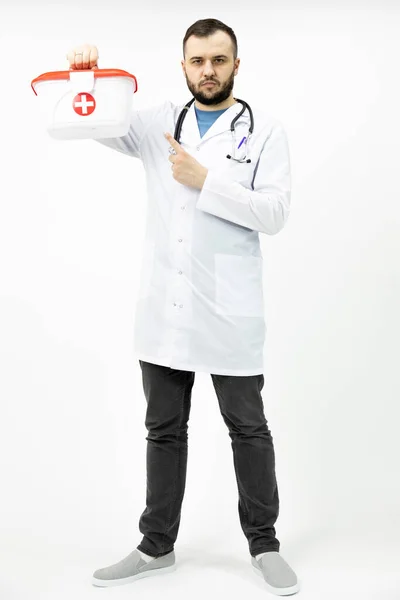 Kızıl Haç sağlık çantası tutan sakallı genç sağlık görevlisi işaret parmağıyla işaret ediyor. — Stok fotoğraf