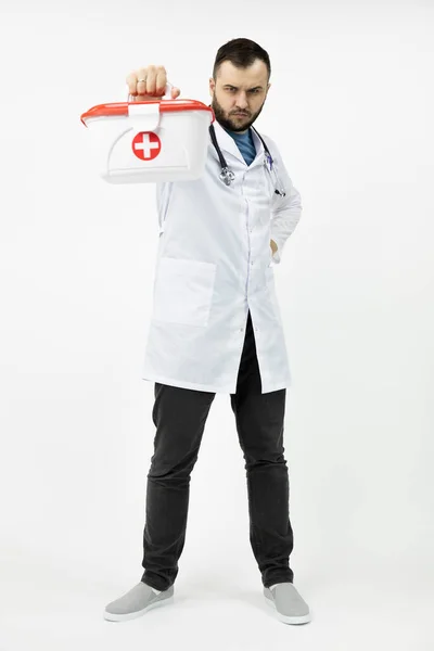 Jeune ambulancier barbu tenant kit médical croix rouge — Photo