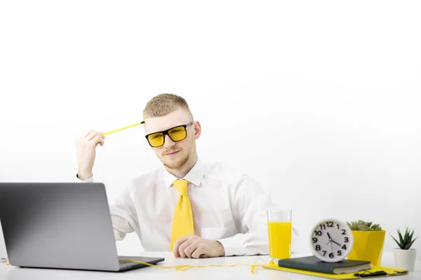 Gerente de óculos amarelos olha atentamente para laptop, acento no pote de suco de gravata amarela — Fotografia de Stock