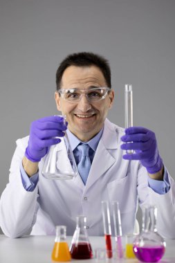 Erkek doktor ya da kimyager mavi eldivenler ve koruyucu gözlük elinde şişe ve tüp