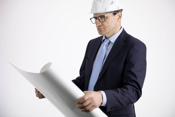 Portrait of architect builder in protective helmet studying layout plan