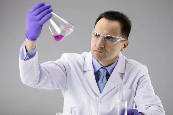 40s Man arts of chemicus onderzoeker nauwkeurig analyseren van rode vloeistof in kolf — Stockfoto