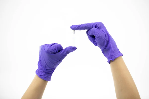 Pequeño recipiente de vidrio con líquido transparente en manos de los médicos con guantes de goma — Foto de Stock