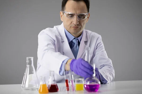 Vegyész kutató kiválasztja lombikok töltött színes kémiai oldatok — Stock Fotó