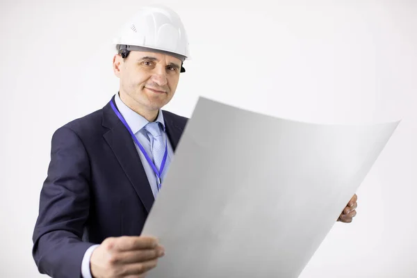Projektleiter mit Hut hält Blaupause in der Hand und blickt lächelnd in die Kamera — Stockfoto