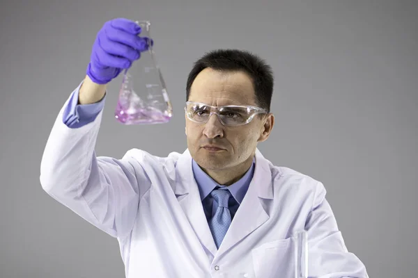 Erkek bilim adamı laboratuvarda reaksiyon tüpleriyle çalışıyor, yeni bileşik sentezliyor. — Stok fotoğraf