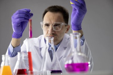 Mavi eldivenli kimyager test tüpündeki çok renkli sıvıyı analiz ediyor.