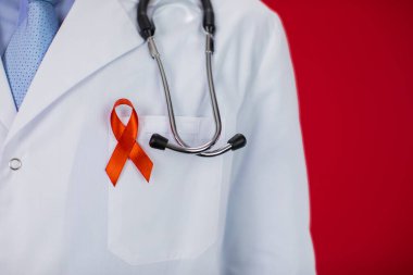 Kırmızı arka planda AIDS için kırmızı kurdeleli 40 'lı yaşlarda bir tıp doktoru.