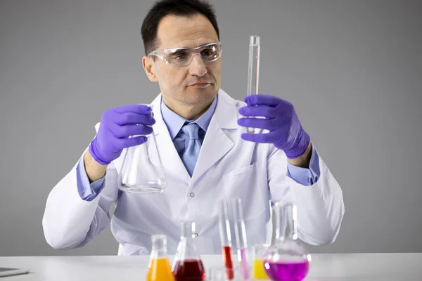 Умный ученый в защитных очках работает в химической лаборатории с реакционными трубками — стоковое фото