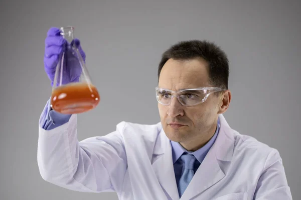 Slimme bioloog doet onderzoek in chemie laboratorium op grijze achtergrond — Stockfoto